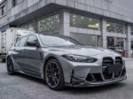 A sleek gray sports car parked outside a modern building on a rainy day.