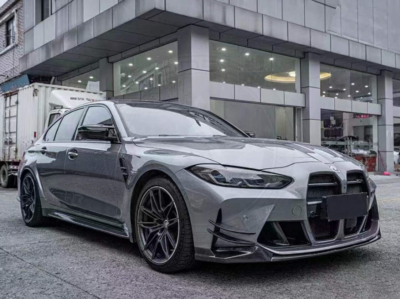 A sleek gray sports car parked outside a modern building on a rainy day.
