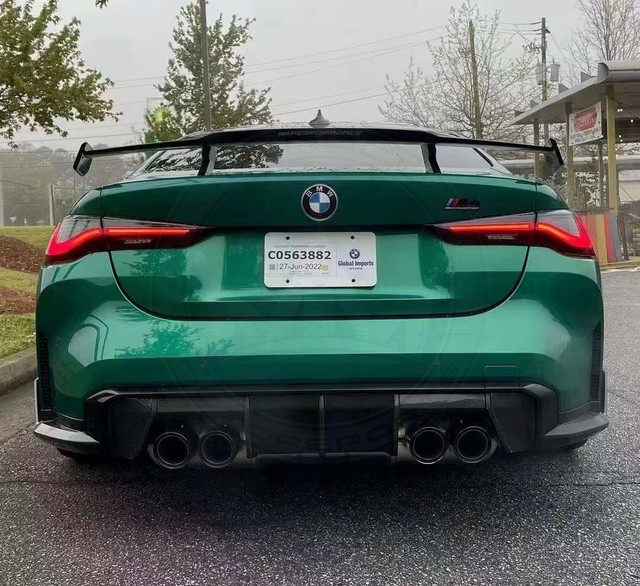 Rear view of a green BMW M4 with quad exhausts and a large spoiler.