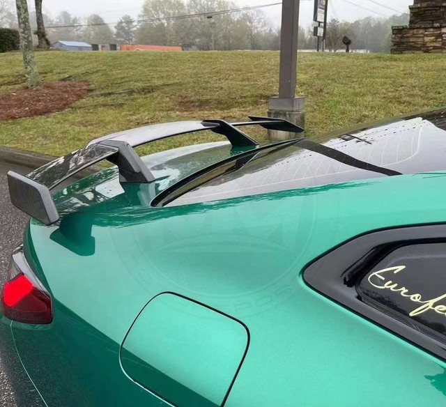 Green sports car with a rear wing and a clear roof panel.